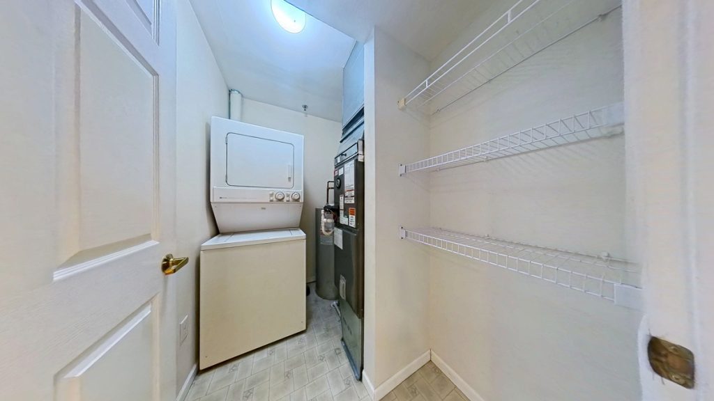 Apartment laundry and storage area with stacked washer and dryer at Emerald Pointe Senior Living in Greenville, Illinois.