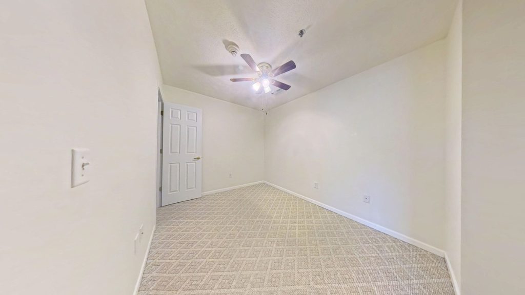 Unfurnished apartment 204 bedroom with carpet and ceiling fan at Emerald Pointe Senior Living in Greenville, Illinois.