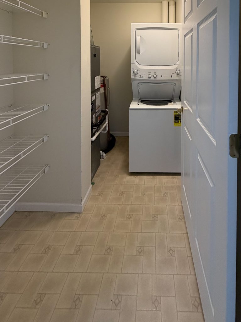 Apartment 204 laundry and storage area with stacked washer and dryer at Emerald Pointe Senior Living in Greenville, Illinois.