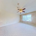 Unfurnished apartment 204 living room with carpet, window, and ceiling fan at Emerald Pointe Senior Living.