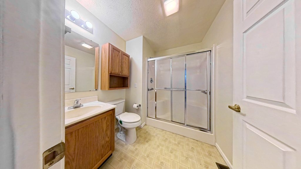 Apartment bathroom with vanity, toilet, and shower at Emerald Pointe Senior Living in Greenville, Illinois.