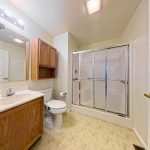 Apartment bathroom with vanity, toilet, and shower at Emerald Pointe Senior Living in Greenville, Illinois.